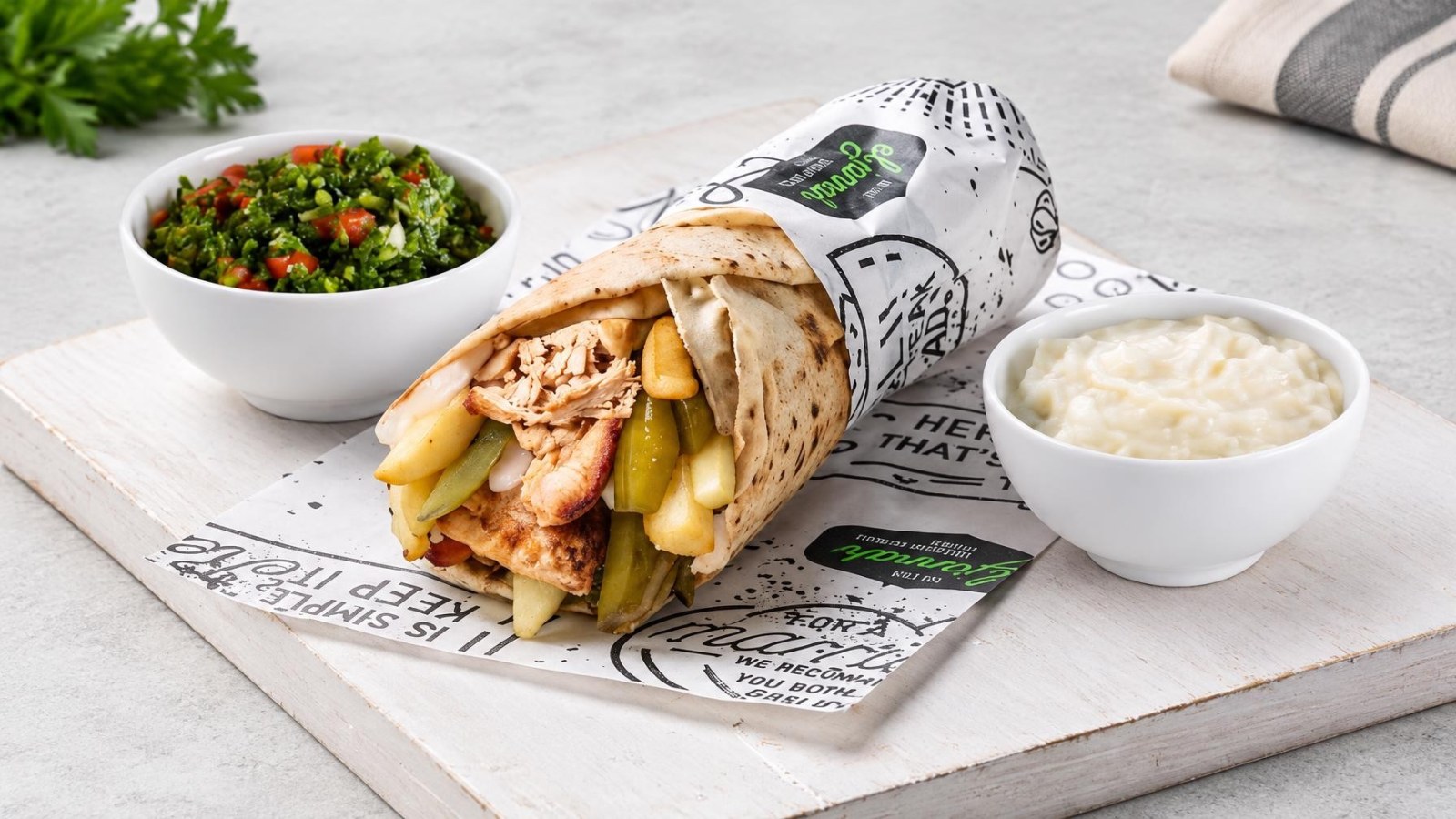 El Jannah Launches $14 Cedars Roll Meal for Rugby League World Cup Until November 15 7 Lebanese charcoal chicken roll wrapped in bread with pickles and chips alongside bowls of tabouli salad and garlic sauce