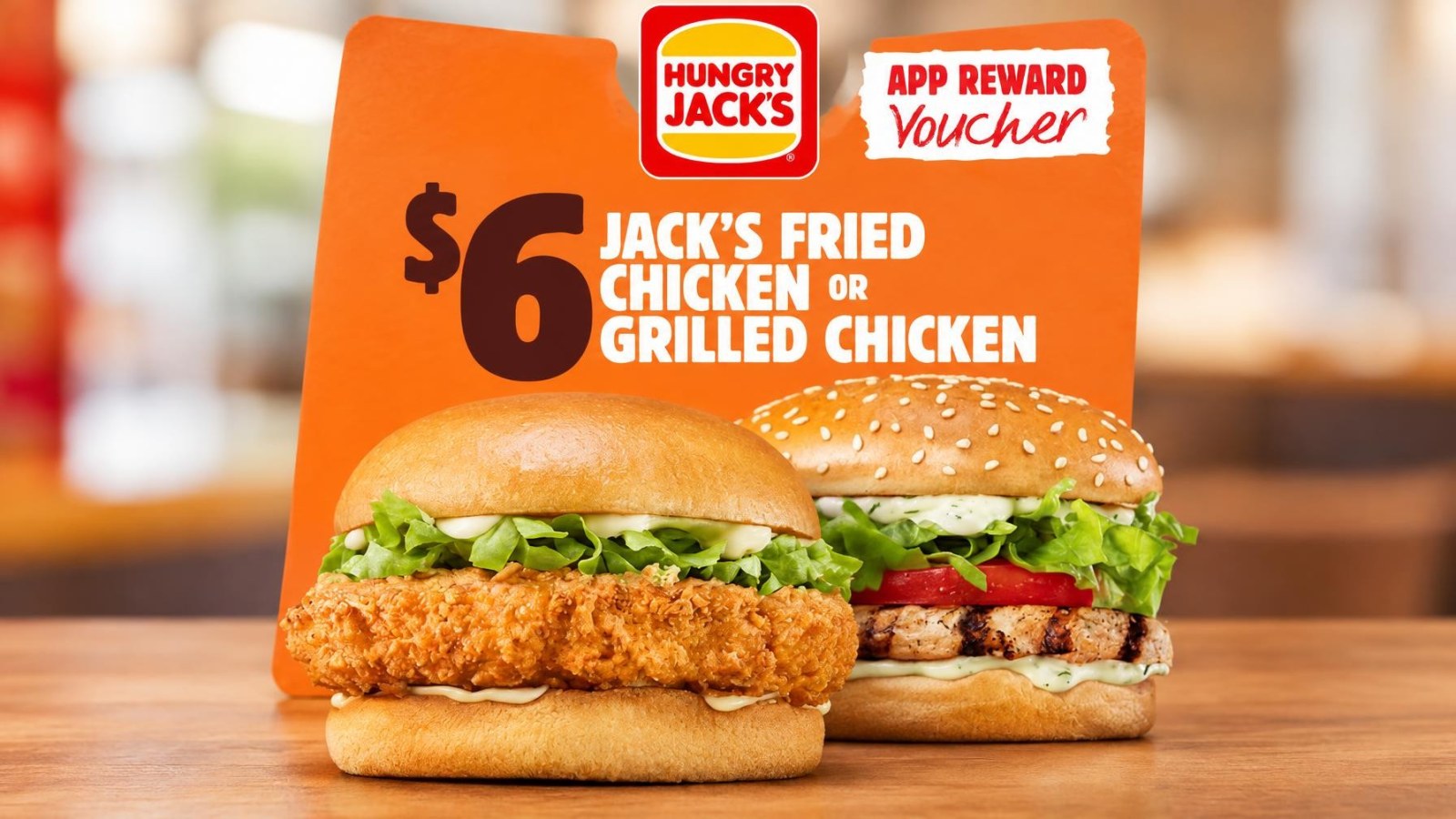 Hungry Jack’s Offers Jack’s Fried Chicken or Grilled Chicken Burger for $6 Until November 9 26 Two chicken burgers placed side by side, one fried and one grilled, with an orange promotional sign behind them showing $6 offer at Hungry Jack's